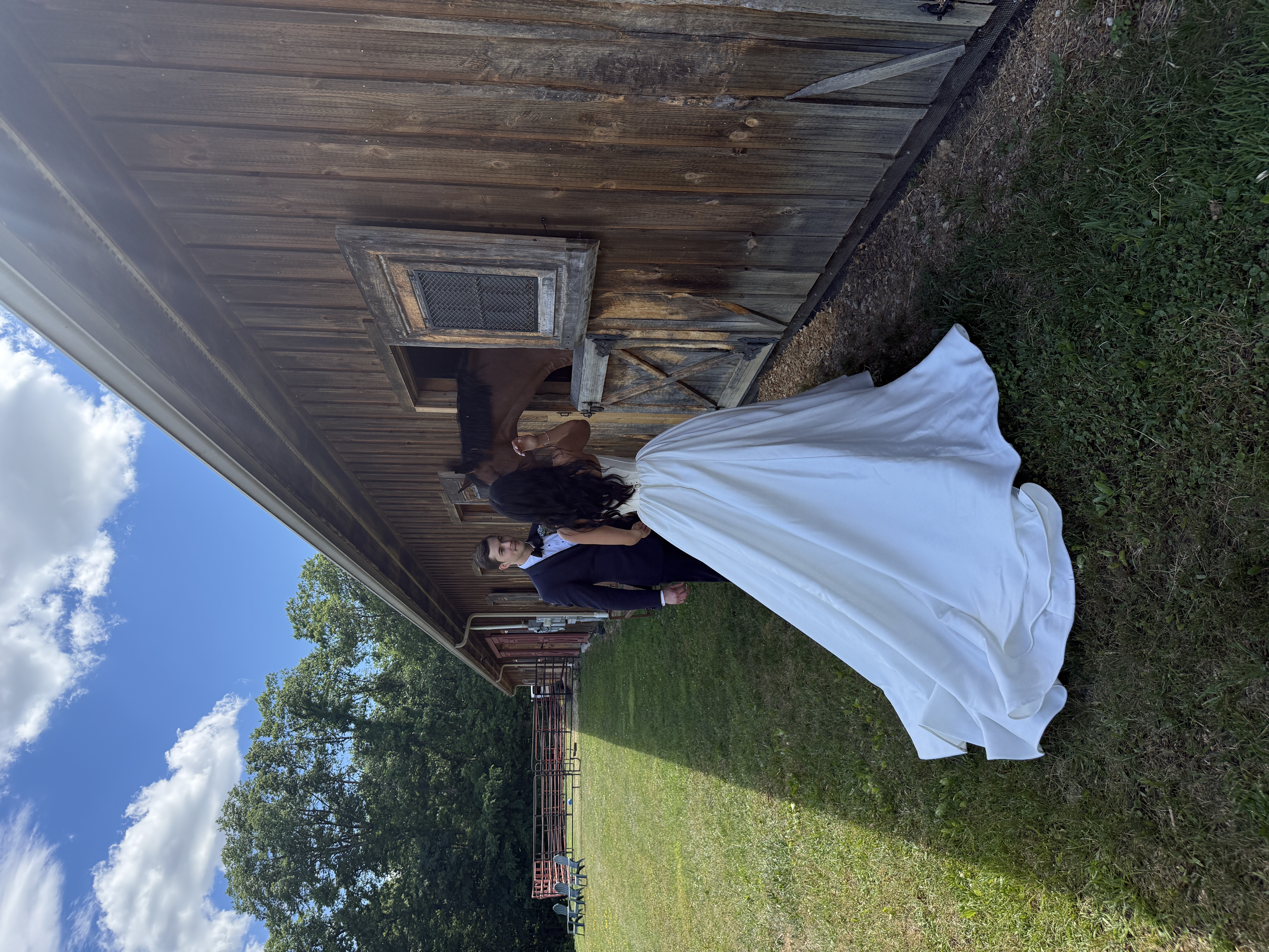 Bride and groom visiting a horse outside a rustic barn on their wedding day